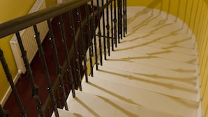 A staircase with a black metal railing, white steps, and a yellow wall. - 16 Pilrig Guest House (Edinburgh)