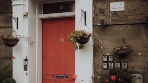 A red door with the number 16, white walls, and a brick facade. - 16 Pilrig Guest House (Edinburgh)