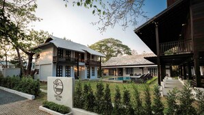 A two-story building with a swimming pool, a covered outdoor seating area, and a sign indicating it is a visitor center. - Chotana Villa (Chiang Mai)