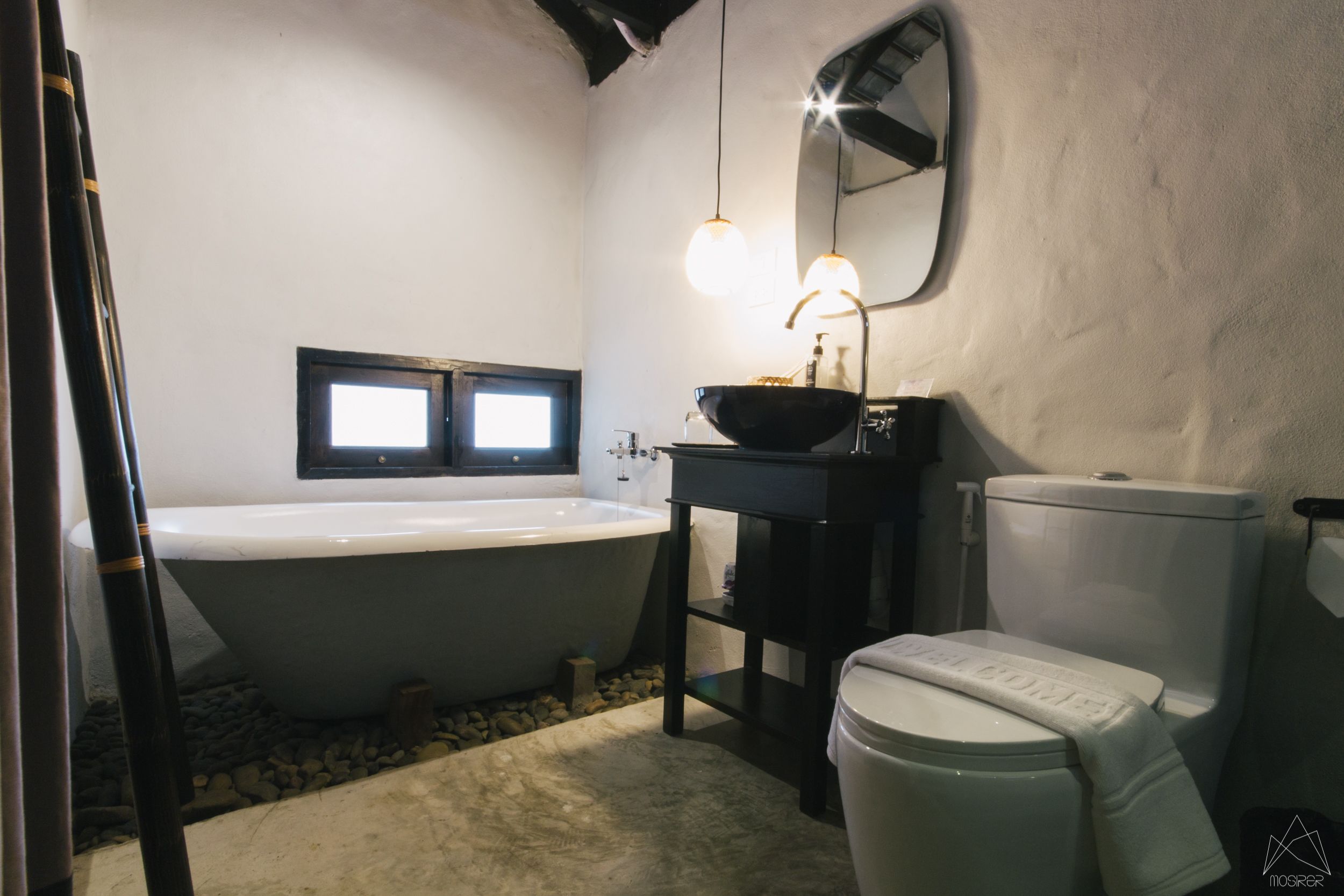 A bathroom with a freestanding bathtub, a sink with a mirror, and a toilet.