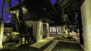 A two-story house with a covered patio, a staircase, and a well-lit exterior at night. - Chotana Villa (Chiang Mai)
