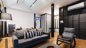 A modern living room with a grey sofa, a black chair, a wooden coffee table, and a black floor lamp. - Chotana Villa (Chiang Mai)