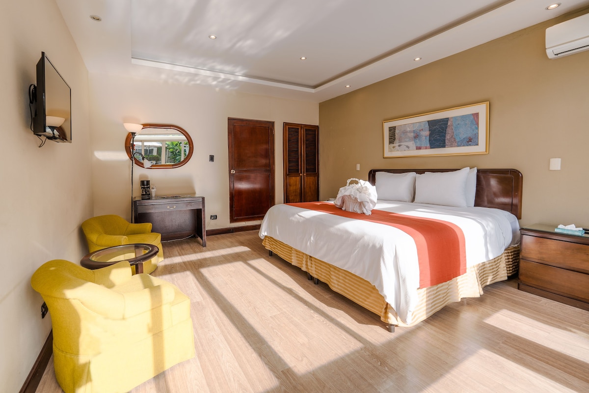 A hotel room with a bed, a desk, a chair, and a wardrobe.