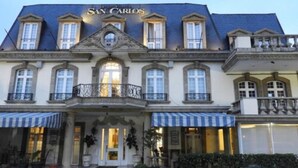 Un edificio histórico con el nombre 'San Carlos' en la fachada. Presenta una fachada simétrica con varias ventanas y una entrada central.