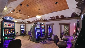 A gaming area with multiple slot machines, chairs, and a wooden ceiling. - Guest House Inn & Suites (Edson)
