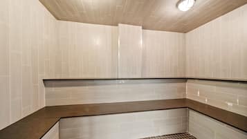 Relax in a serene sauna room with a dark brown bench and light-colored tiles.