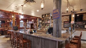 A bar area with wooden bar stools, a granite countertop, and a sign indicating the bar offers mineral water. - Guest House Inn & Suites (Edson)