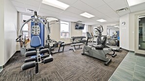 A well-equipped gym with various exercise machines, a blue chair, and dumbbells. - Guest House Inn & Suites (Edson)