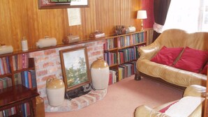 Una sala de estar acogedora con un sofá de cuero, una chimenea, una estantería y una pared de madera.