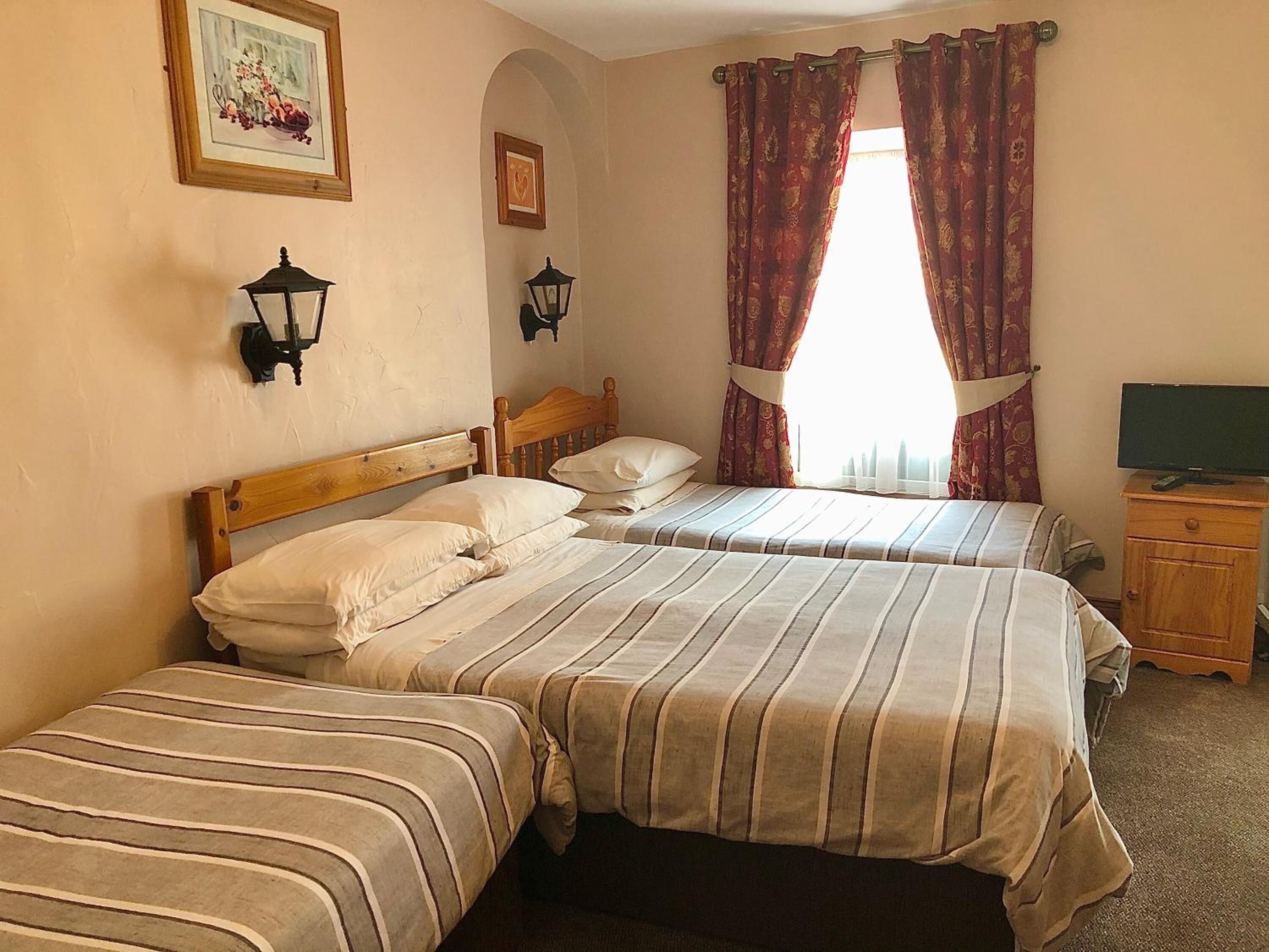 A hotel room with two beds, a television, and a small wooden cabinet.