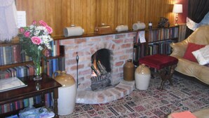 Una habitación acogedora con chimenea, paredes de madera, un sofá y una estantería llena de libros.