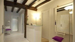 A hallway with a reception desk, a chair, a mirror, and a door. - Artea Narrika (San Sebastián)