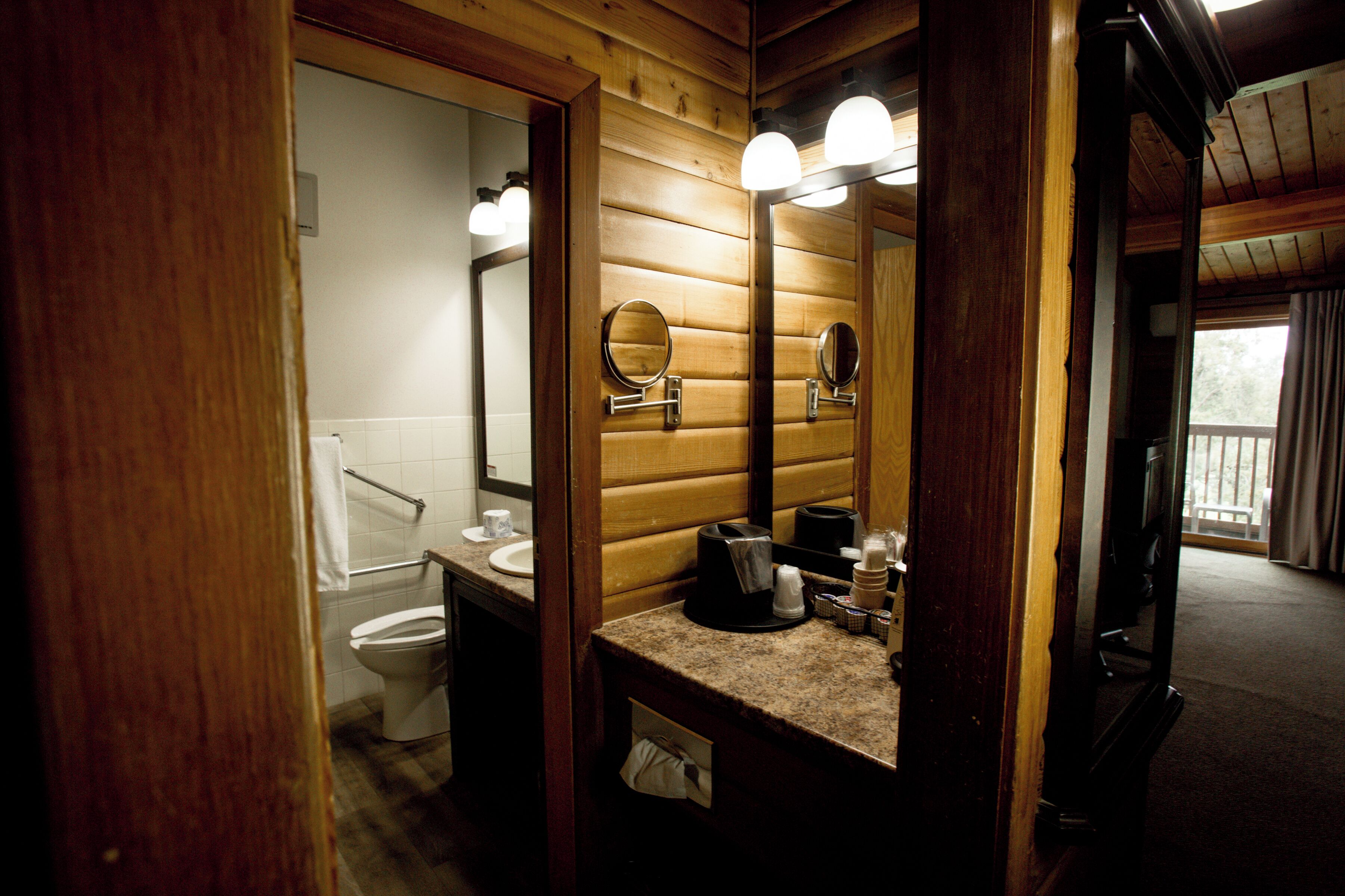 Un bagno con arredamento in legno, dotato di lavabo, specchio e water.