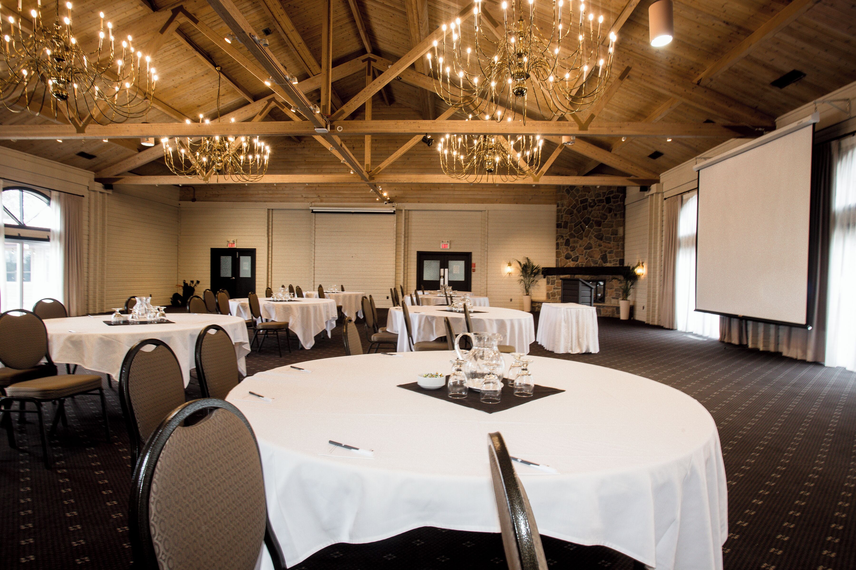 A conference room with multiple round tables, white tablecloths, and chairs.