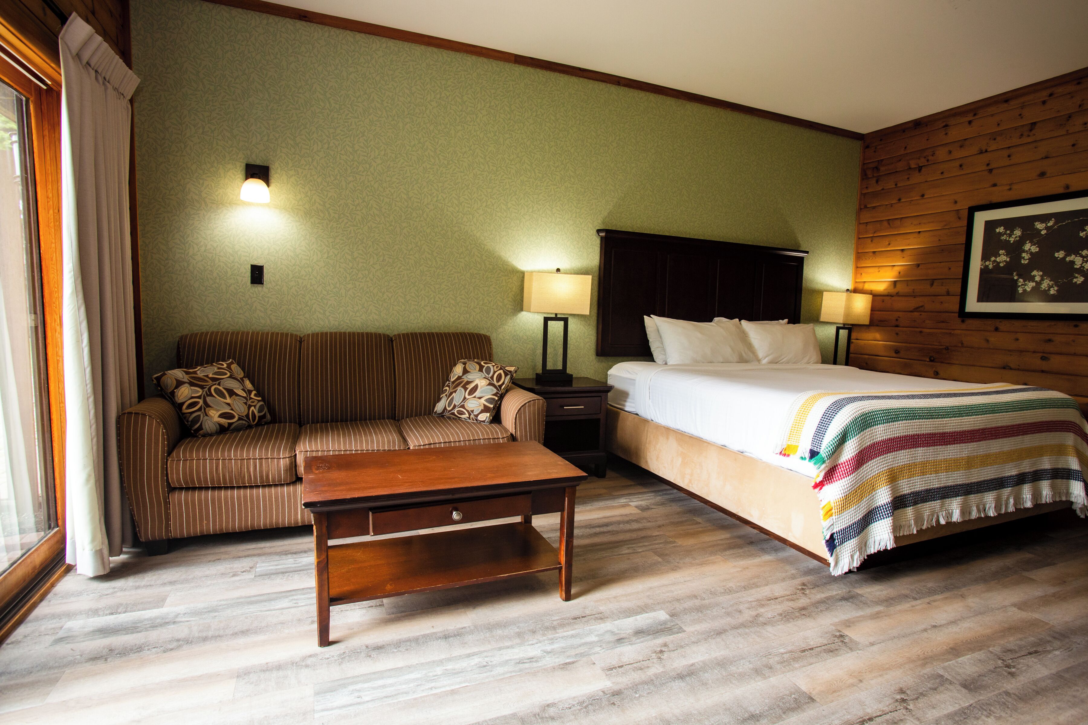 Habitació d'hotel amb un llit, un sofà, una tauleta de nit i una taula.