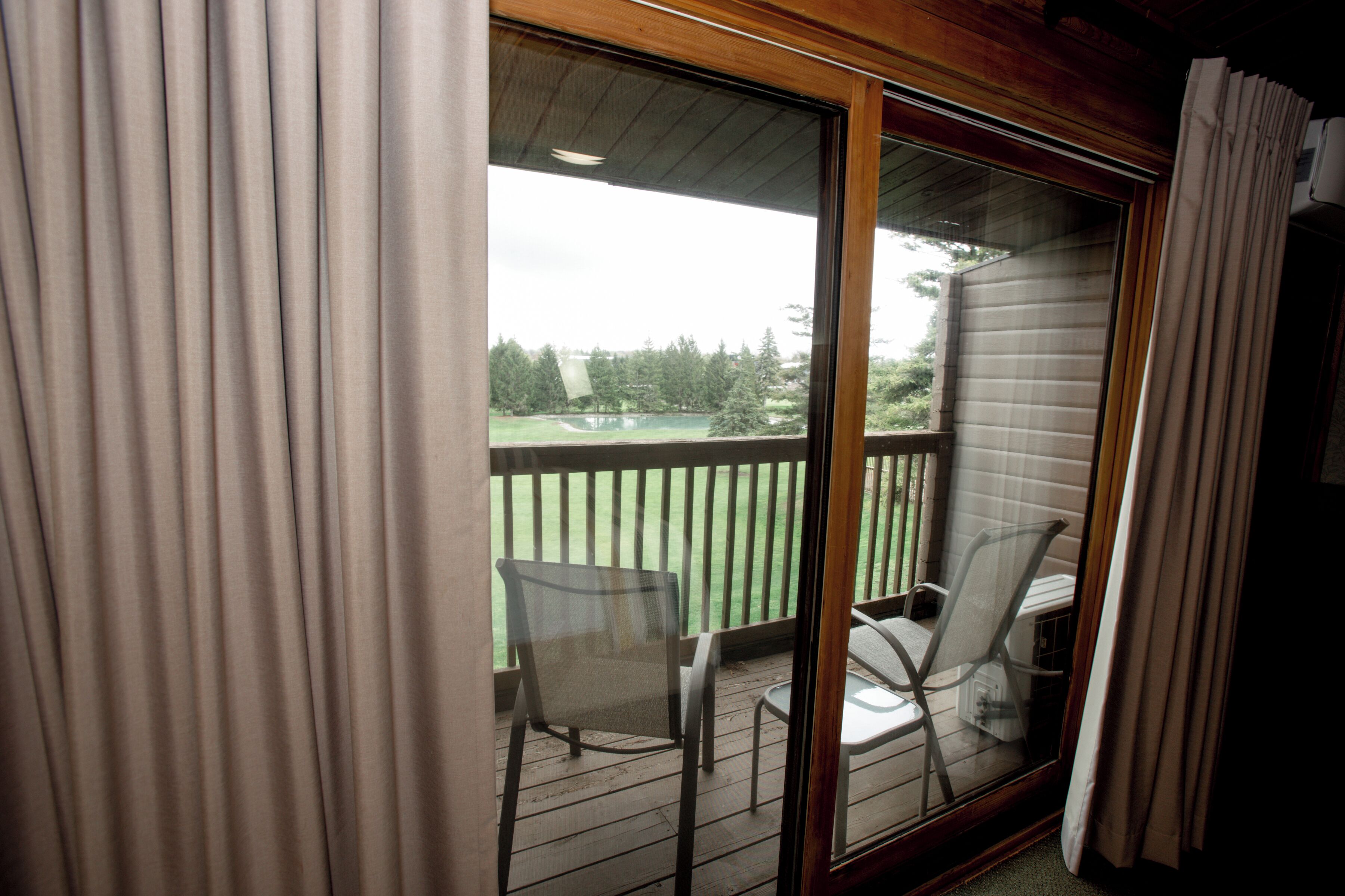 Un balcón con vistas a un paisaje verde y una terraza de madera.