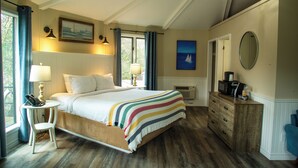 A bedroom with a large bed, bedside lamps, a dresser, and a mirror. - Oakwood Resort (South Huron)