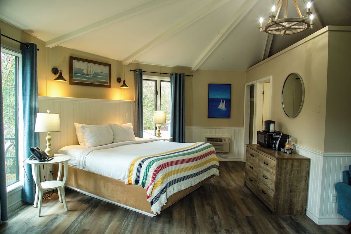 Quarto com cama grande, luminárias de cabeceira, cômoda e espelho.