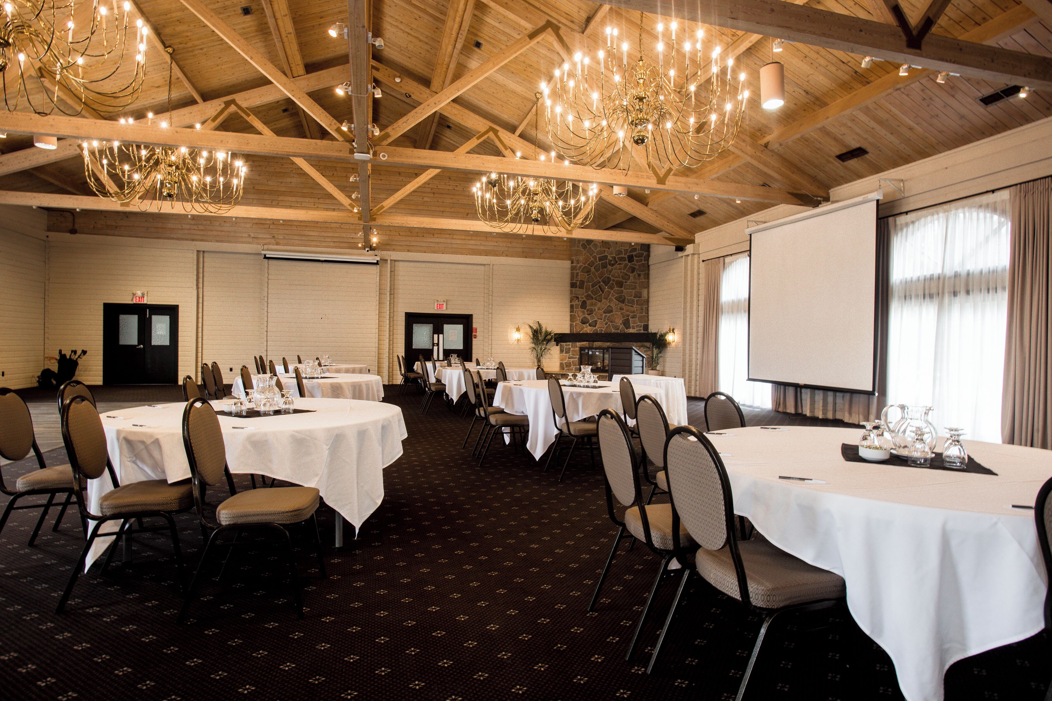 A conference room with round tables, chairs, and a projector screen.