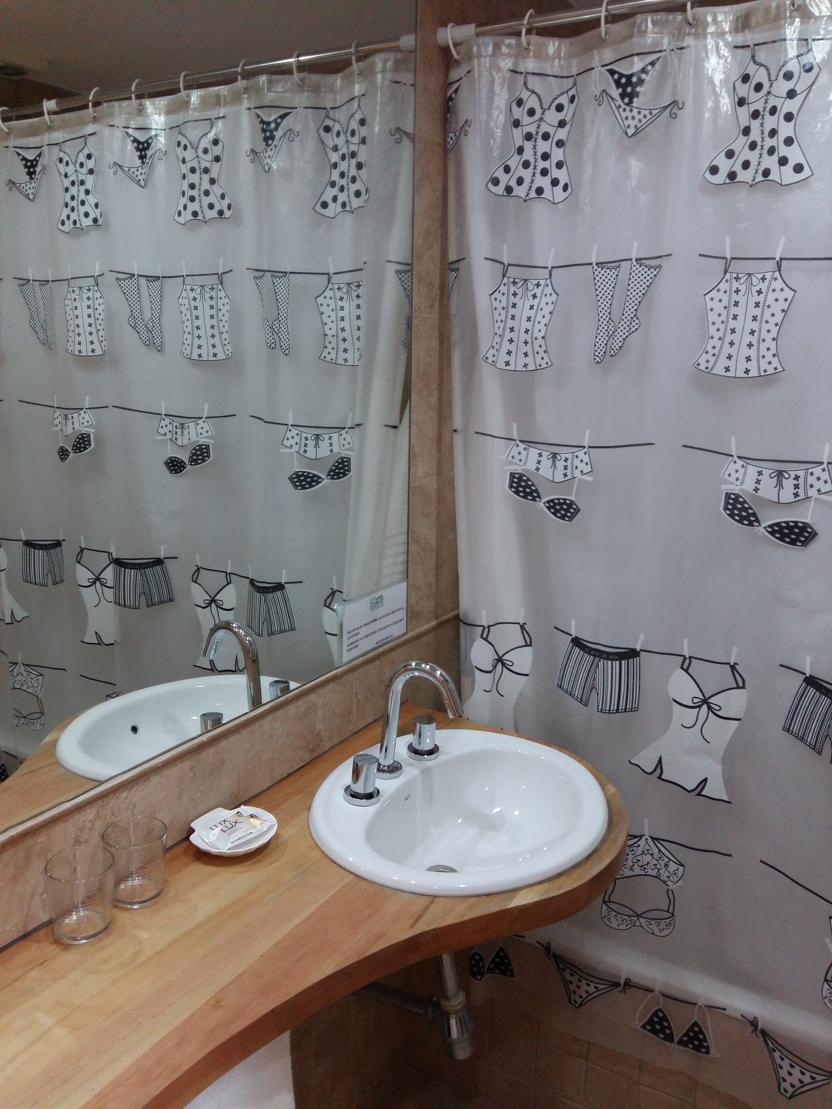 A bathroom with a white sink, mirror, and a shower curtain with black and white patterns.