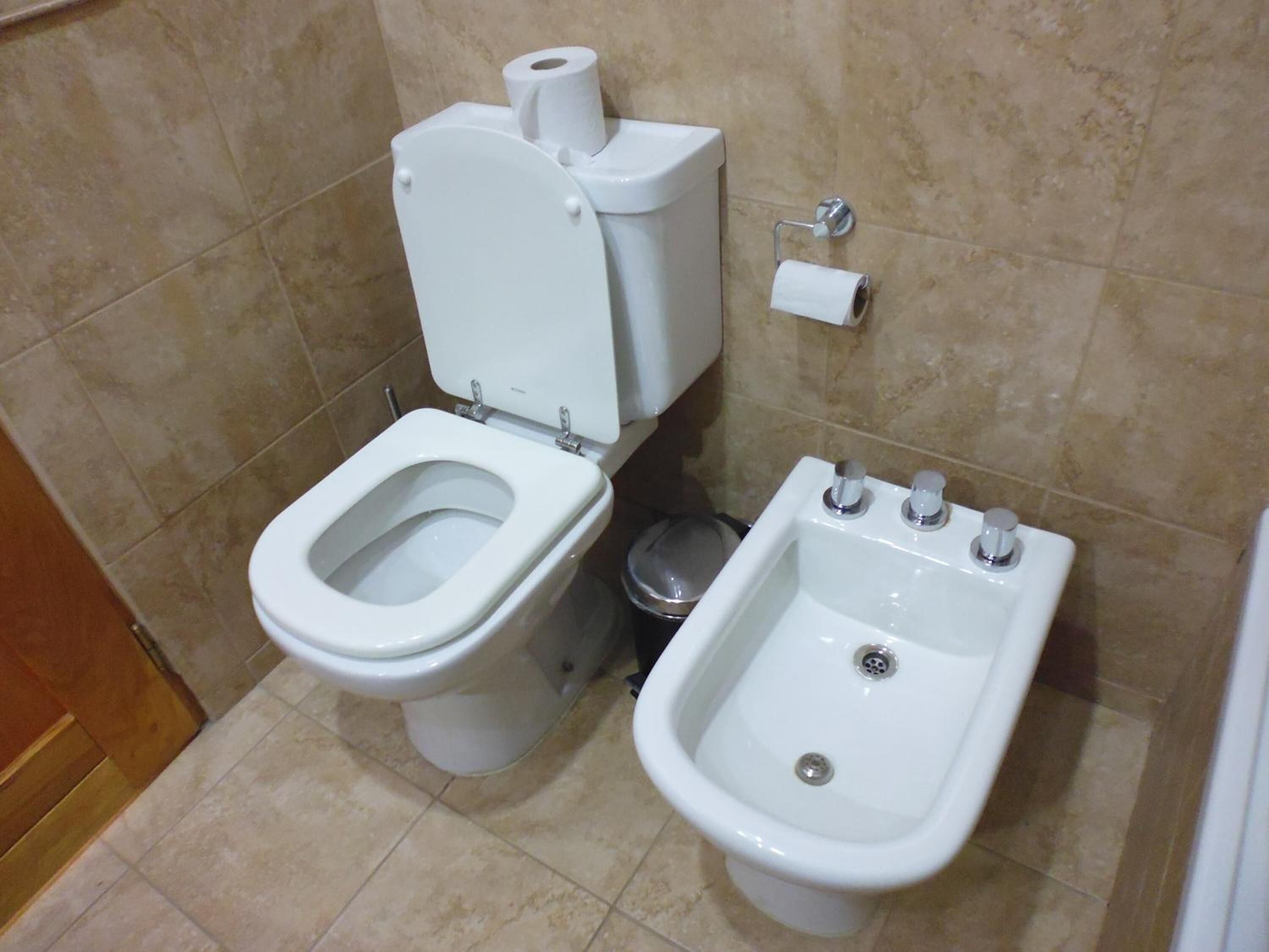 Une salle de bain équipée de toilettes, d’un bidet et d’une poubelle.