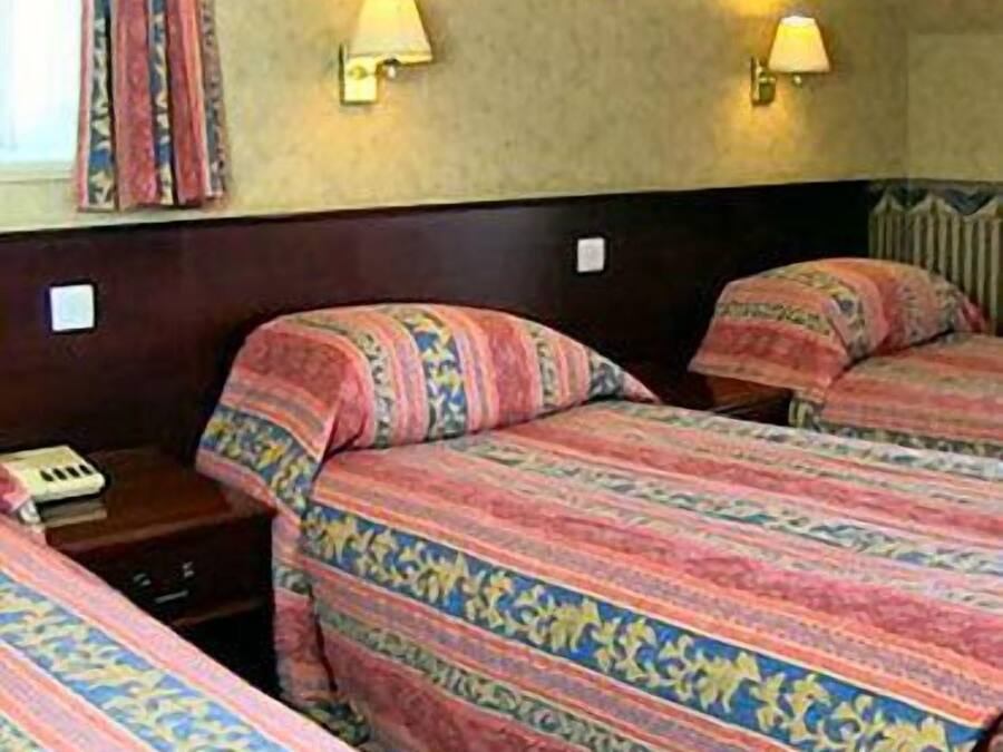 Ett hotellrum med två sängar, där varje säng har mönstrat sänglinne, sänglampor och ett litet bord med en telefon.