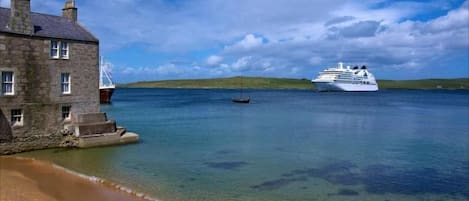 Escena costera con un edificio, un ferry y un crucero.