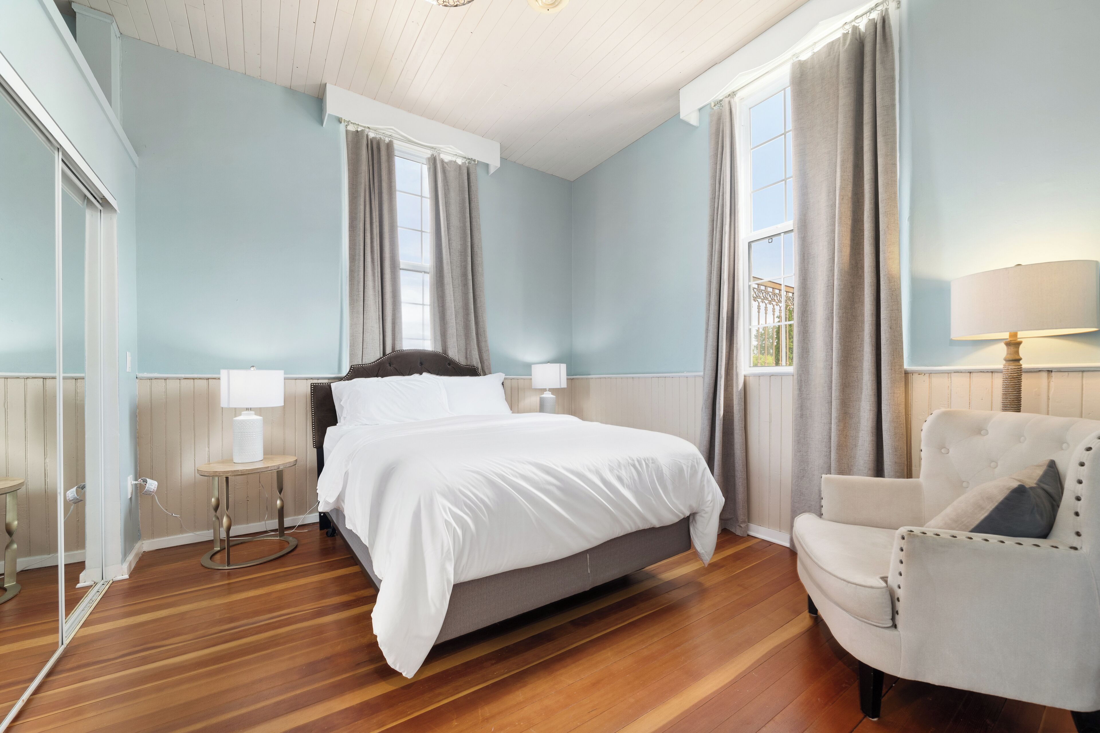 A bedroom with a bed, bedside tables, a chair, and a window with curtains.