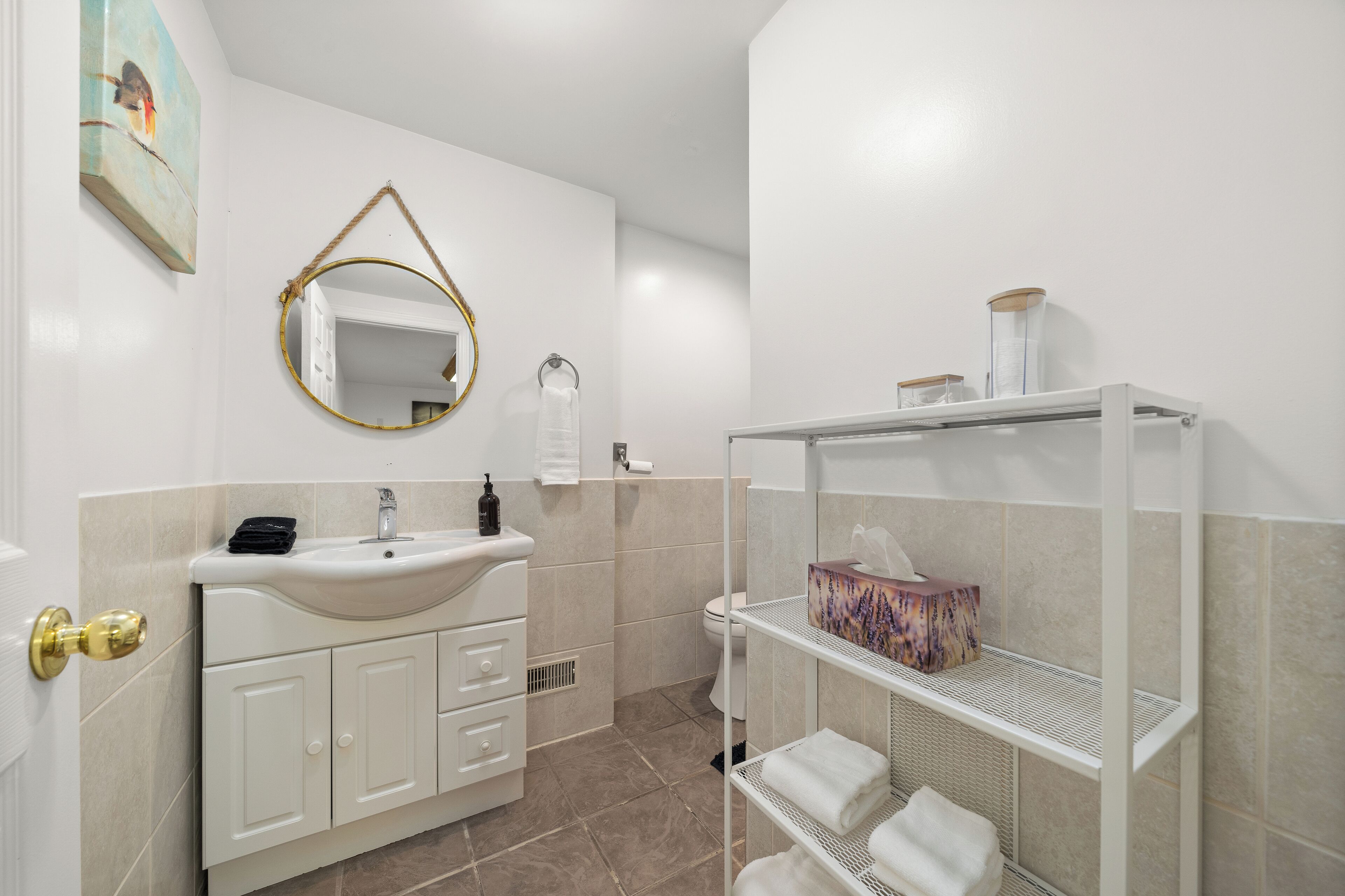 A modern bathroom with a white sink, a mirror, and a shelf with towels.
