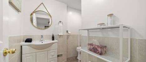 A modern bathroom with a white sink, a mirror, and a shelf with towels.