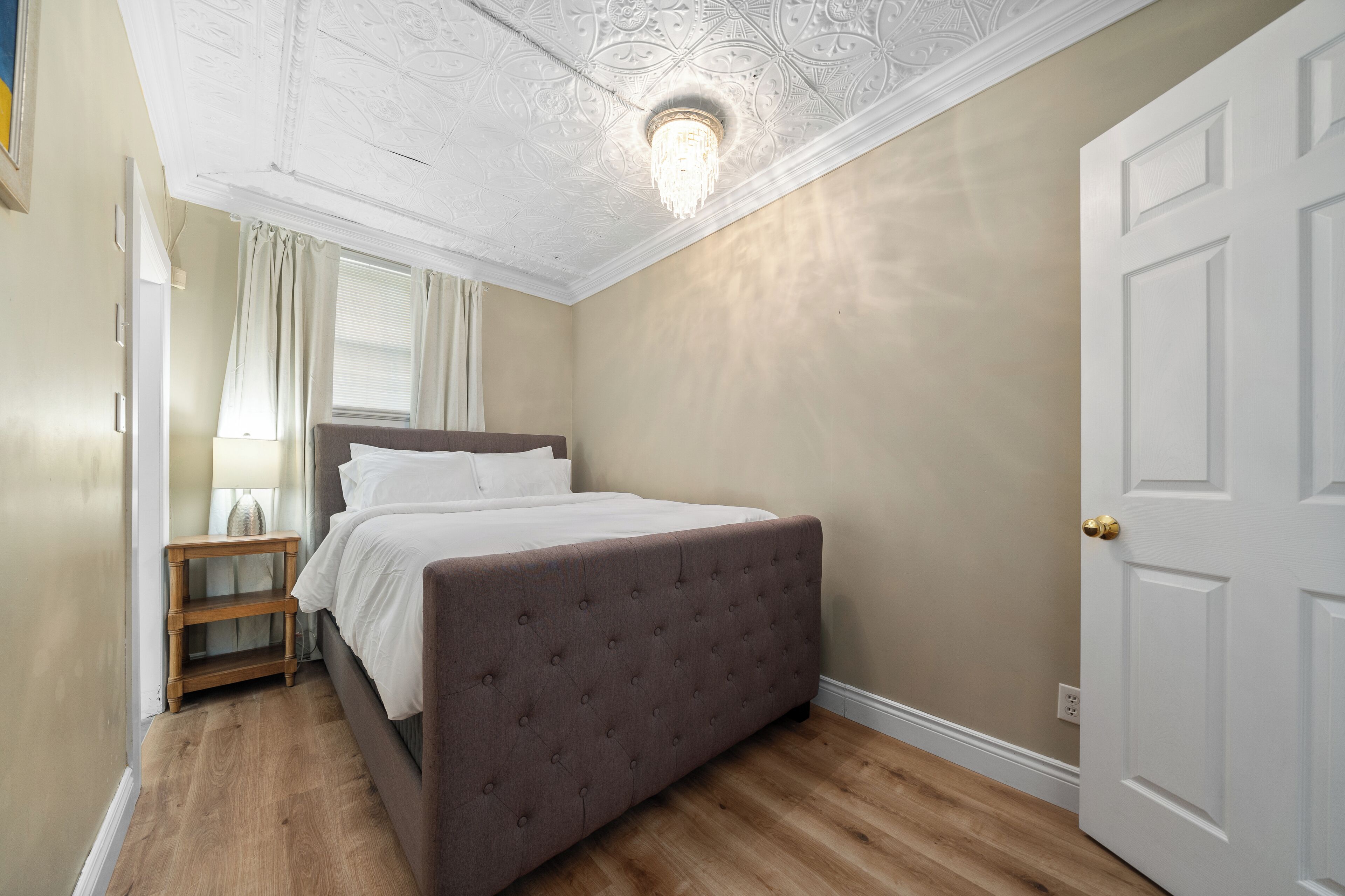 Un dormitorio con una cama grande, una mesita de noche, un candelabro y una puerta.