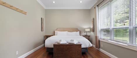 A bedroom with a bed, a ceiling fan, a bedside table, and a window with blinds.