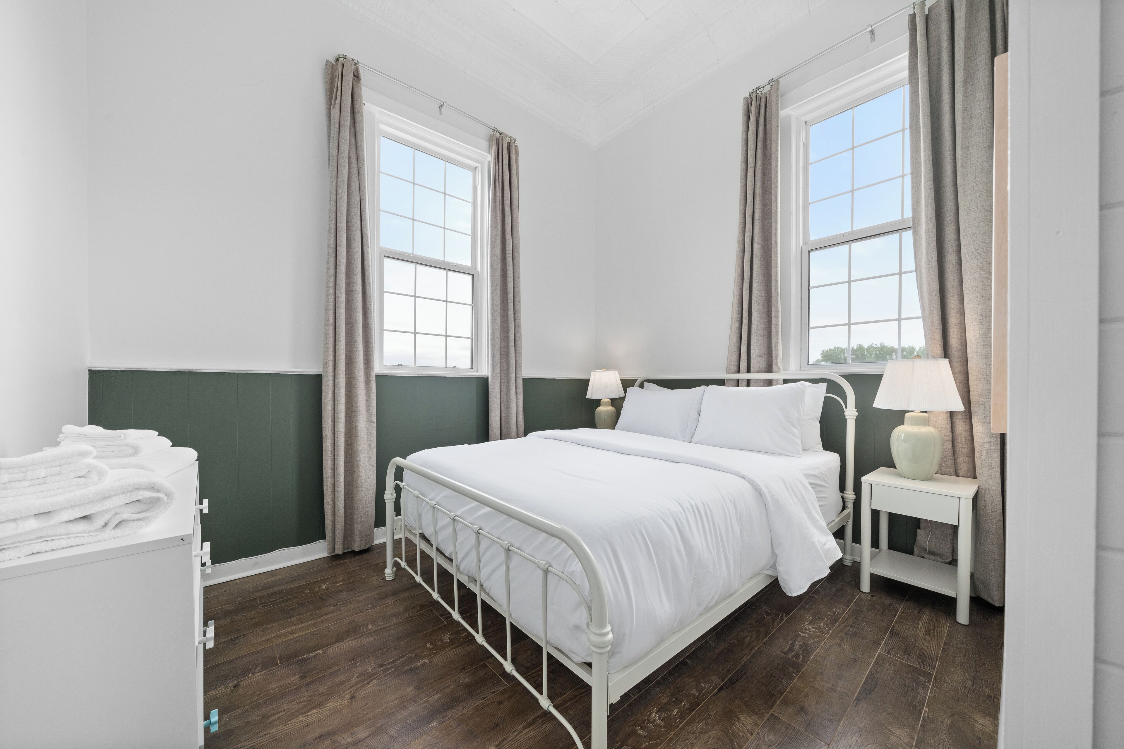 Une chambre à coucher bien rangée, avec un lit, des tables de chevet et une commode.