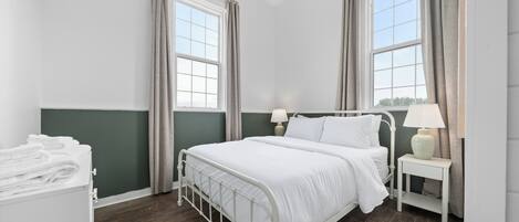Une chambre à coucher bien rangée, avec un lit, des tables de chevet et une commode.