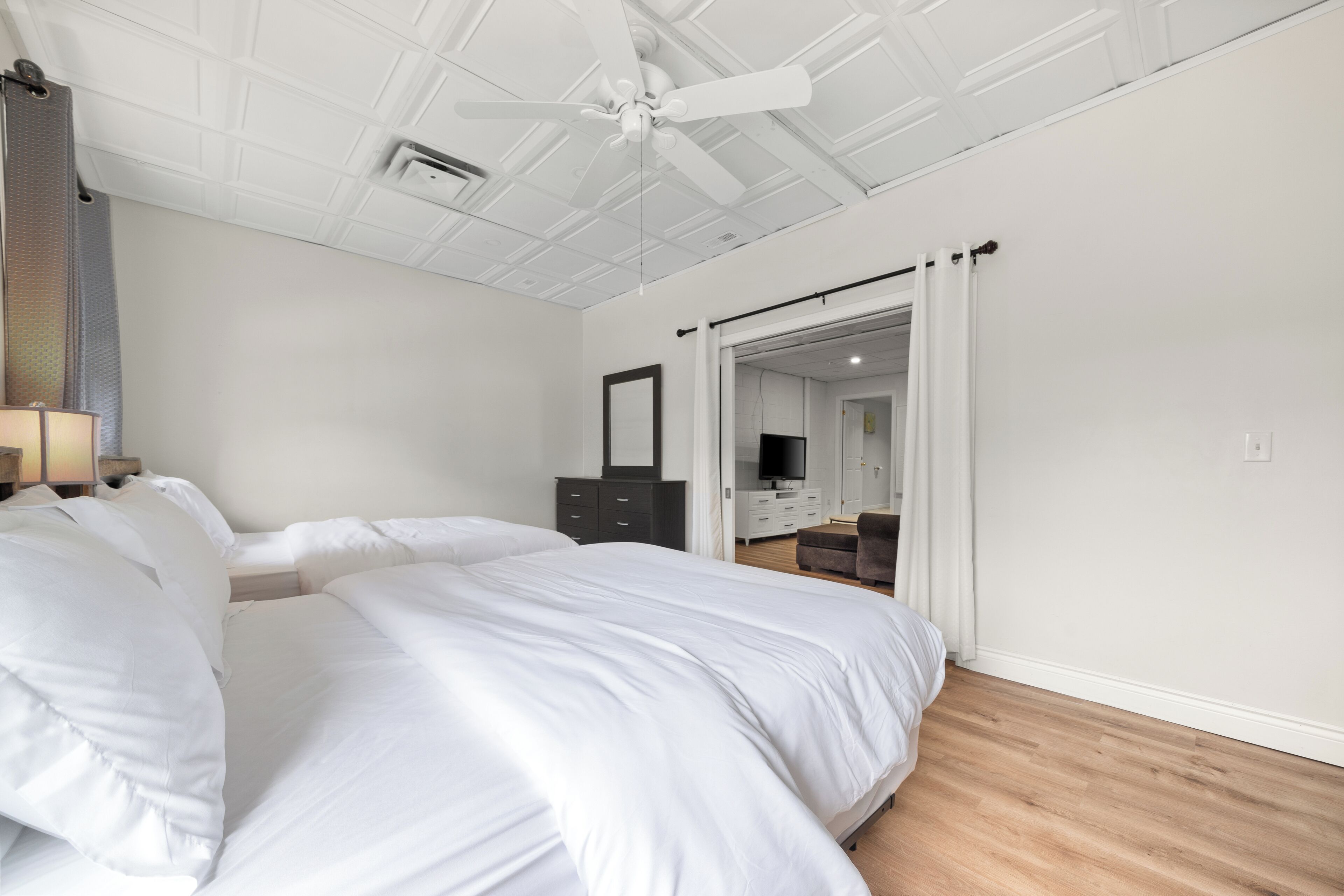 Ein Schlafzimmer mit einem großen Bett, einem Deckenventilator, einem Kleiderschrank und einem Spiegel.