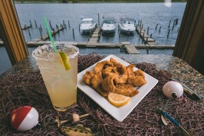 A table with a plate of fried seafood, a margarita with a lime wedge, and a view of boats on water. - Sportsman's Lodge (Baudette)