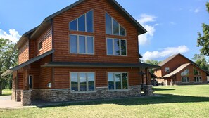 A two-story log cabin with a stone foundation, large windows, and a sloped roof. - Sportsman's Lodge (Baudette)