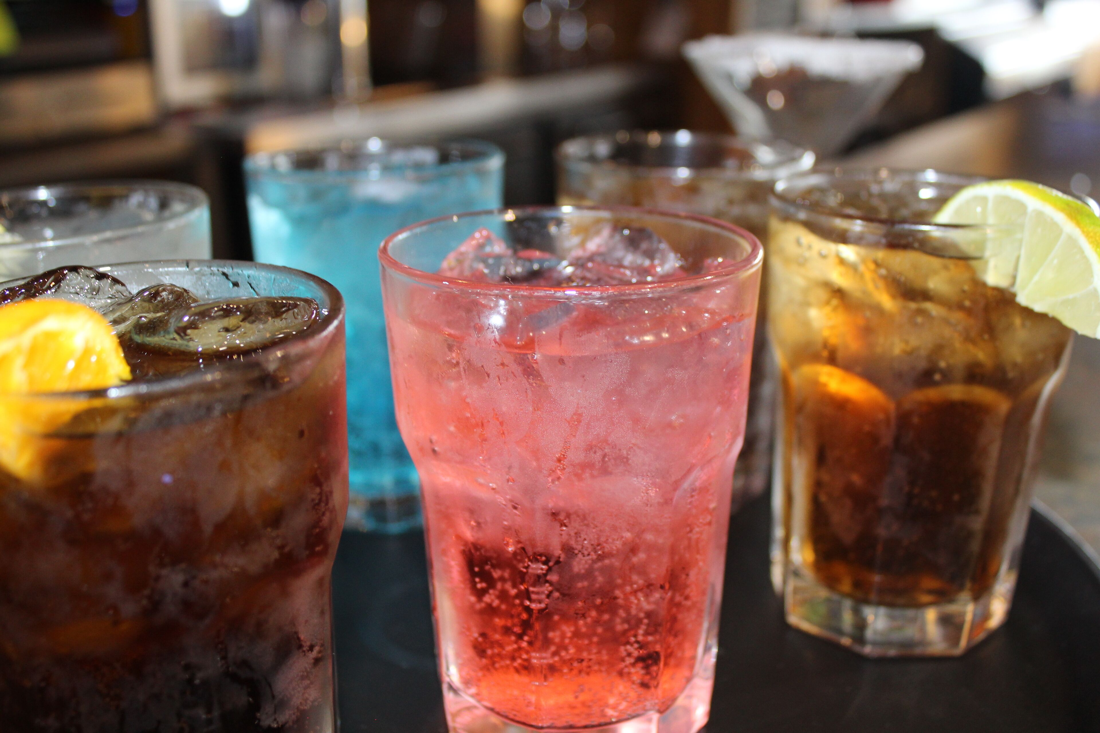 A variety of drinks in glasses with ice and garnishes.