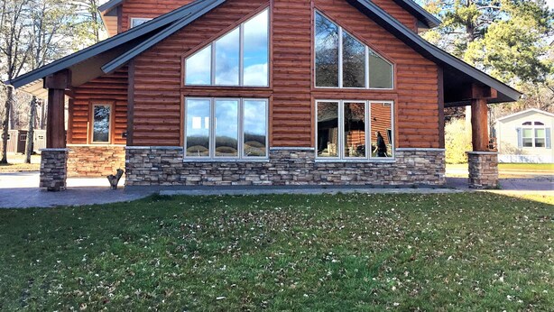 A log cabin with a stone foundation, large windows, and a sloped roof. - Sportsman's Lodge (Baudette)