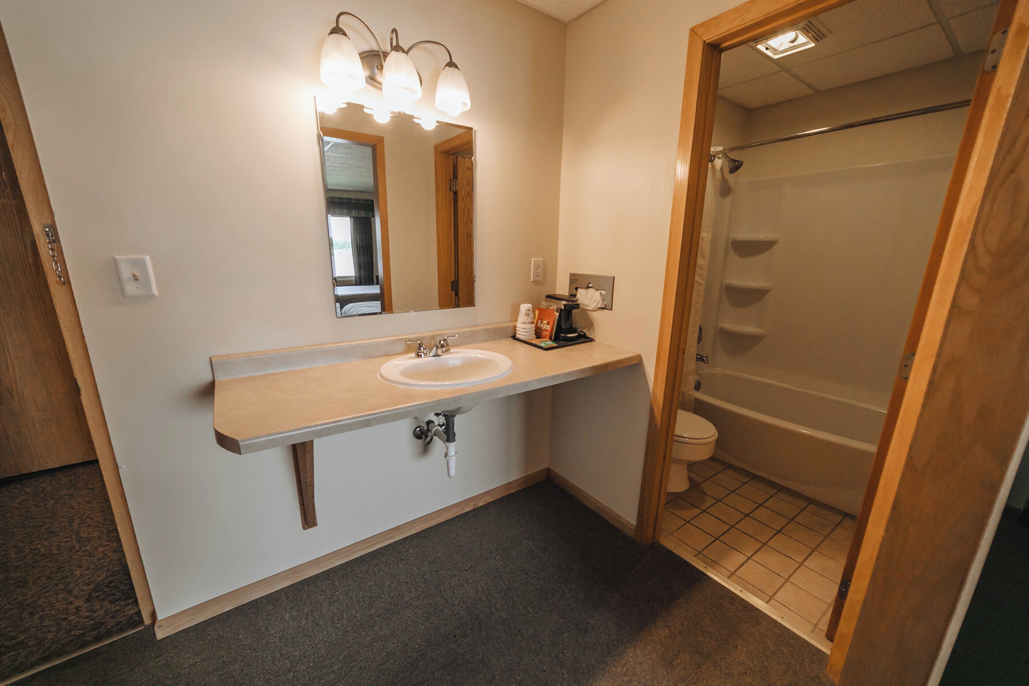 A bathroom with a sink, mirror, and shower.