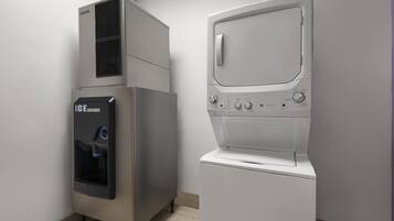 Uma lavanderia com máquina de lavar de carregamento frontal e dispensador de gelo industrial.