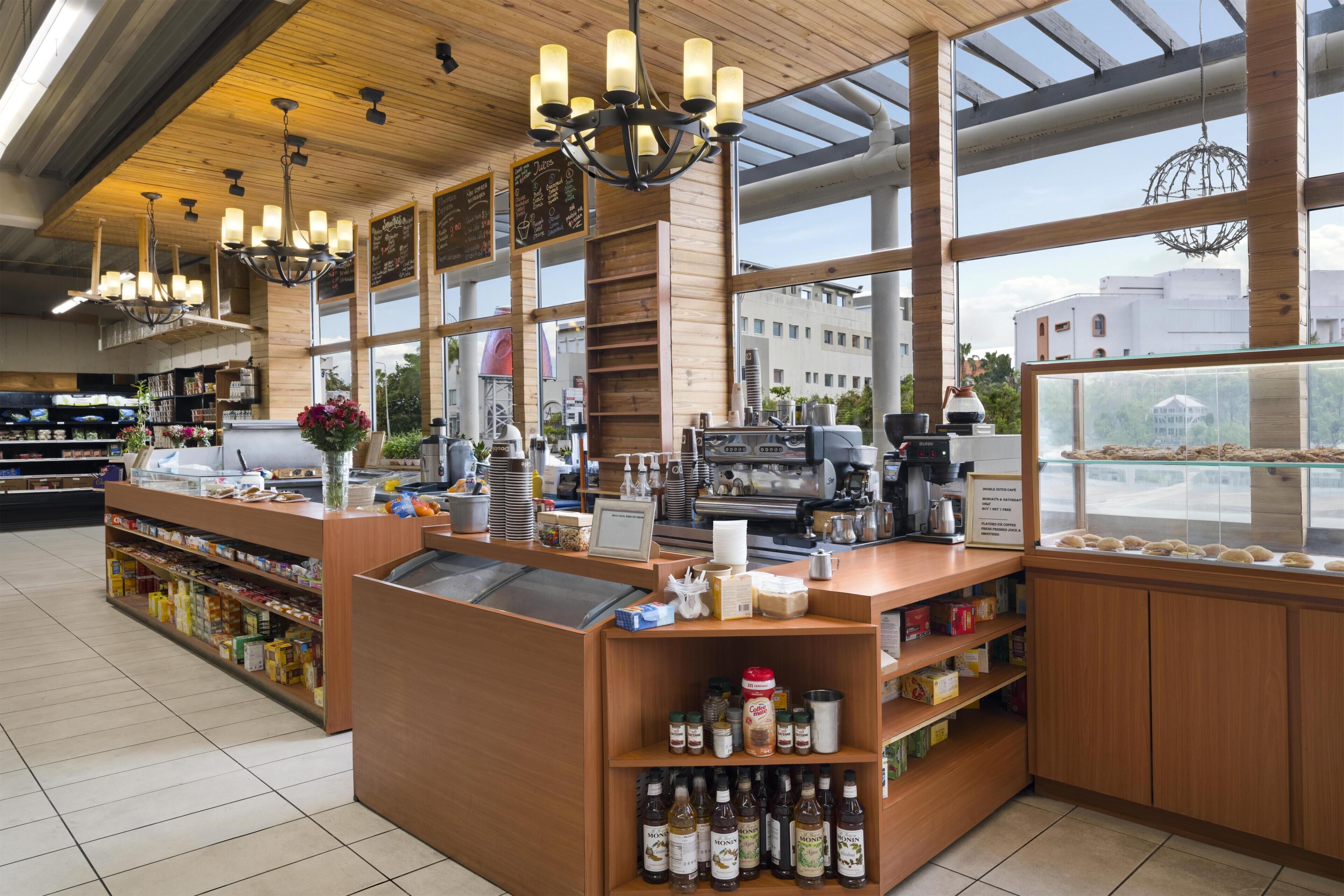 A cafe interior with wooden accents, a coffee machine, and a view of the city through large windows.