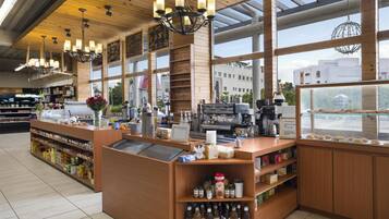 A cafe interior with wooden accents, a coffee machine, and a view of the city through large windows.