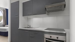 A modern kitchen with grey cabinets, a stainless steel countertop, and a built-in oven. - Commodore Suites, SureStay Collection by Best Western (Simpson Bay)