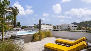 A rooftop with a hot tub, yellow lounge chairs, and a view of buildings and mountains. - Commodore Suites, SureStay Collection by Best Western (Simpson Bay)