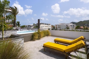 A rooftop with a hot tub, yellow lounge chairs, and a view of buildings and mountains. - Commodore Suites, SureStay Collection by Best Western (Simpson Bay)