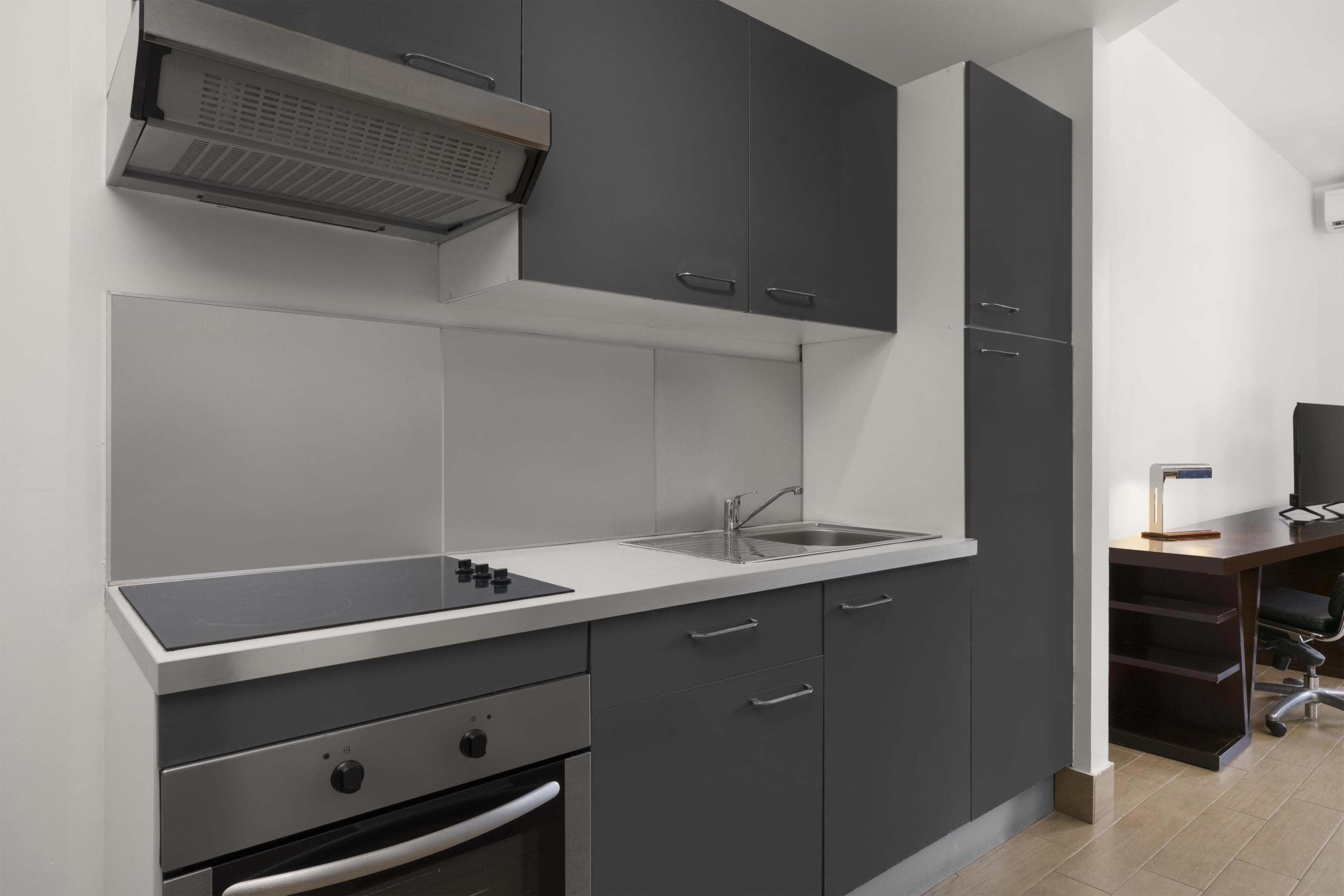 Eine moderne Küche mit grauen Schränken, einer Edelstahl-Spüle und einem eingebauten Backofen.