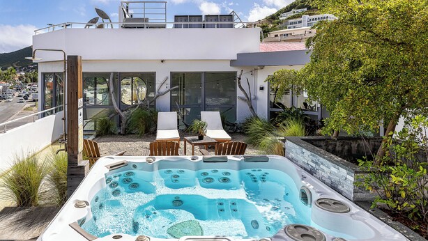 A modern house with a hot tub in the backyard, surrounded by outdoor furniture and plants. - Commodore Suites, SureStay Collection by Best Western (Simpson Bay)