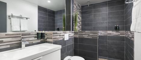 Un baño moderno con un lavamanos blanco, inodoro y zona de ducha.