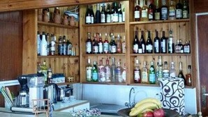 A bar area with wooden walls and shelves stocked with various bottles.